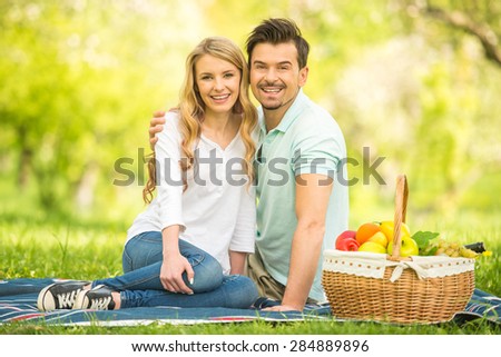 Young beautiful couple having picnic on the lawn in summer park.