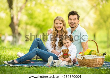 Image of happy young family having picnic outdoors.