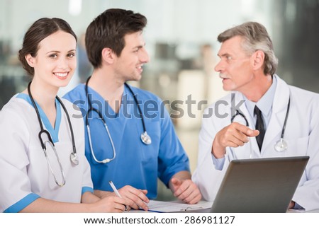 Group of doctors working together on a laptop at doctor\'s office.