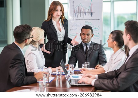 Young business people in suits sitting at meeting room and listening speaker.