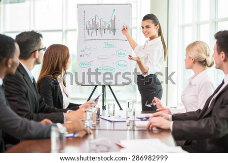Business woman pointing at a growing chart during a meeting,