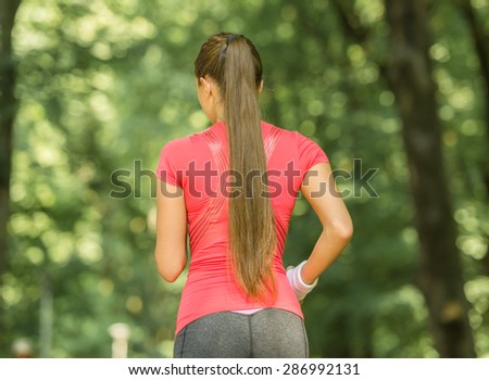 Back view of sporty young woman jogging at park in the morning.
