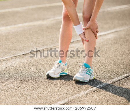 Female athlete runner touching foot in pain due to sprained ankle.