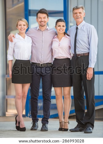 Group of successful office workers standing in front of office together and looking at camera.