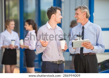 Confident business people having coffee break while standing in front of office.