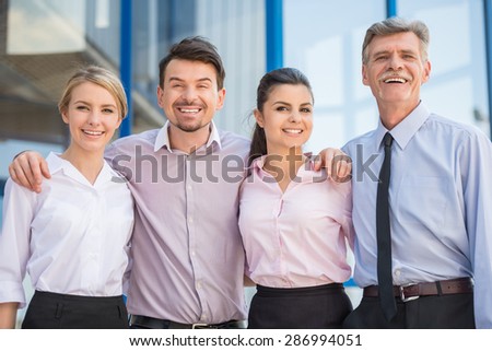 Group of successful office workers standing in front of office together and looking at camera.