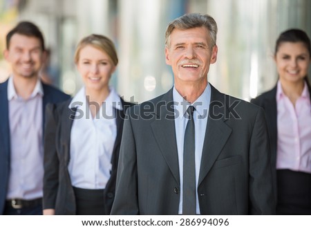 Group of business people standing in front of office and looking at camera.
