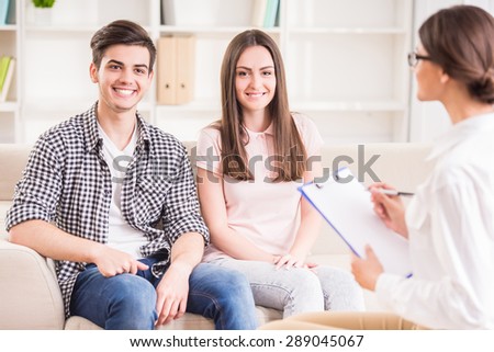 Happy young couple talking to psychotherapist during therapy session.