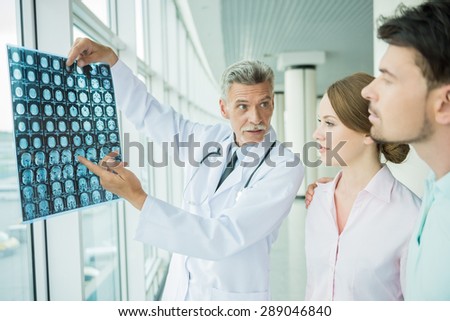 Experienced male doctor showing his patients X-ray results at diagnostic centre.