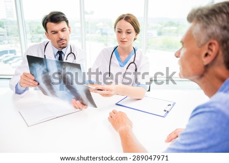 Doctors and patient discussing X-ray results in diagnostic center.