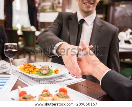 Two elegant business partners shaking hands while having business lunch. Great deal agreement.