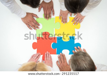 Group of business people assembling jigsaw puzzle and represent team support and help concept. Close-up.