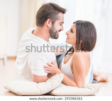 Young family couple relaxing together on the floor at home, looking to each other.