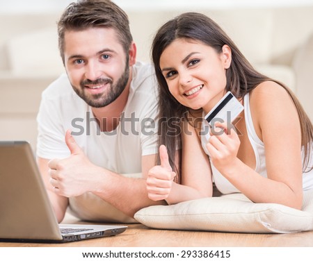 Young beautiful couple lying on the floor at home and making order online.