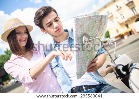 Young couple sitting on scooter and reading map. Romantic jorney.