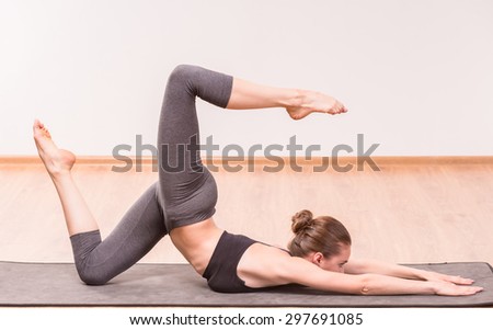 Pretty young brunette practicing yoga on mat.