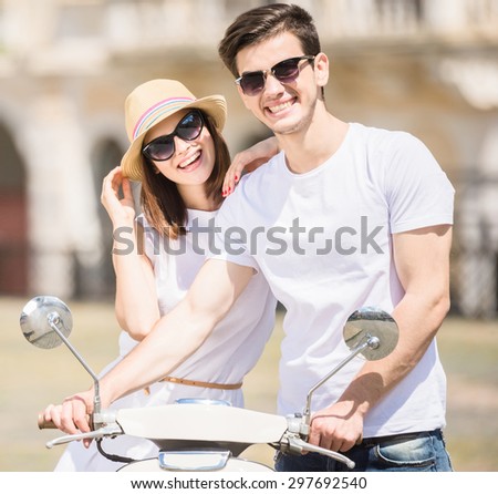 Beautiful young couple smiling to camera while woman sitting on scooter. Romantic journey.