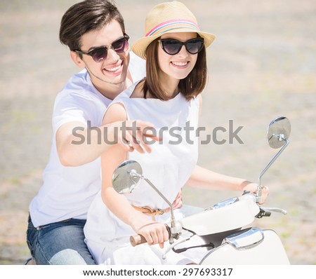 Beautiful young couple having fun together on sunny day outdoors, man pointing away.