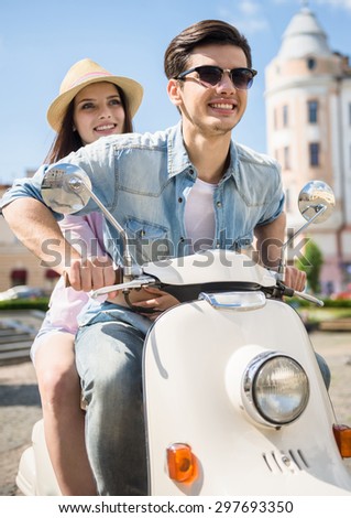 Beautiful young couple riding scooter together, woman hugging her boyfriend.