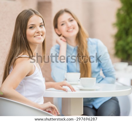 Two beautiful young women meeting for coffee at urban cafe in summer.