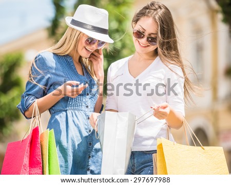 Two beautiful women looking inside shopping bags in the city.