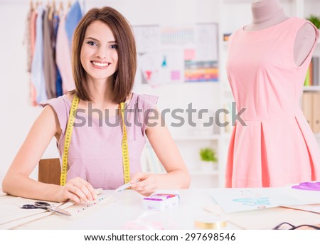 Female fashion designer sitting in her office near mannequin and smiling at camera.