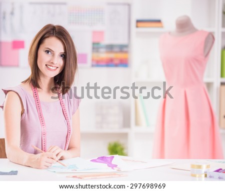 Young female fashion designer drawing sketch with model sitting in her office.