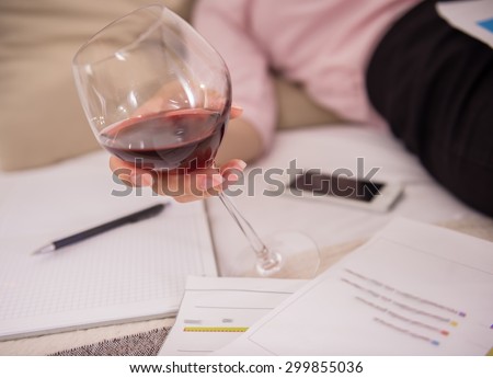 After hard working day. Tired young woman sleeping on bed with glass of wine and documents at the hotel room. Close-up.