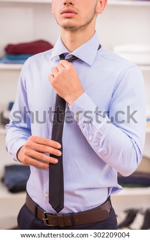 Man in shirt adjusting tie on neck. Close-up.
