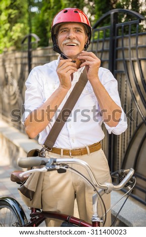 Smiling senior man is wearing helmet, is going to riding bicycle.
