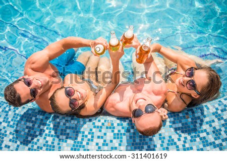 Top view of beautiful young people having fun in swimming pool, smiling and drinking beer.