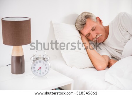 Senior man is sleeping in comfortable bed at home.