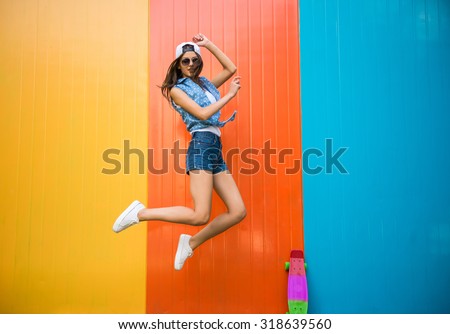 Pretty young woman is jumping with against the colorful wall.