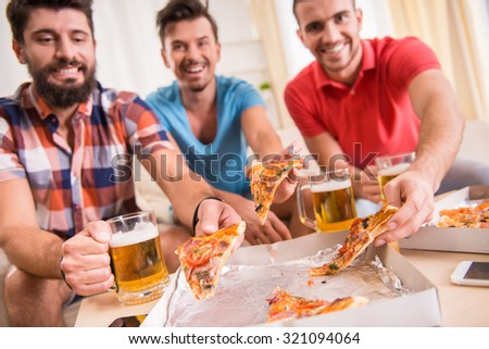 Young men drink beer, eat pizza and cheering for football