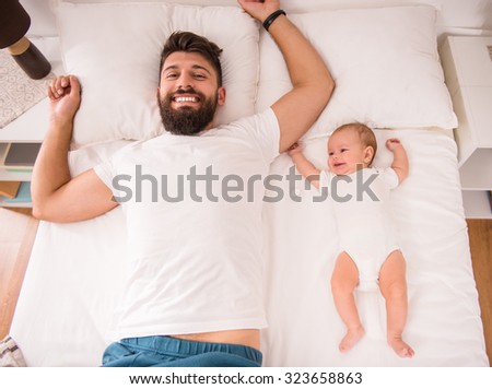 Portrait of a happy young father with a baby in the bed at home