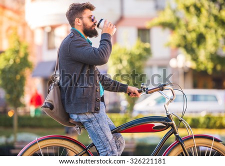 City bike. A young man with a beard, walk the city with bike