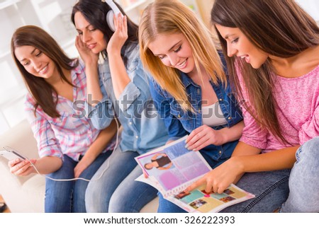 Group of young girls sitting on the couch at home and watching magazine.
