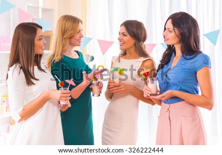 Young beautiful girls drink cocktails at home party.