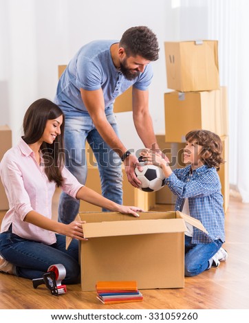 Young happy family moving to a new home, opening boxes