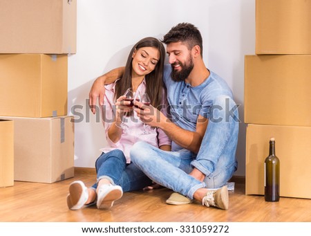 Young happy couple drinking wine, celebrating moving to new home, moving to a new home