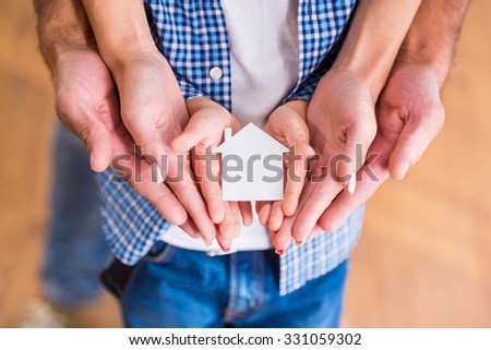 Hands of a happy young family holding little house, moving to a new home