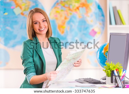 Portrait of a young woman chooses a place to travel using map sitting in office travel agency