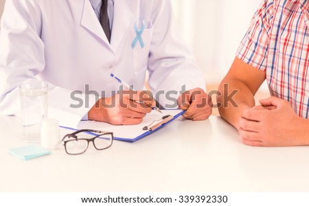 The social problem of male diseases. Portrait of doctor and patient man with a blue ribbon sitting in the office