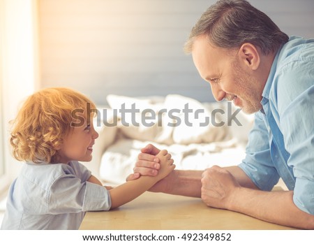 Handsome grandpa and grandson are wrestling and smiling while spending time together at home