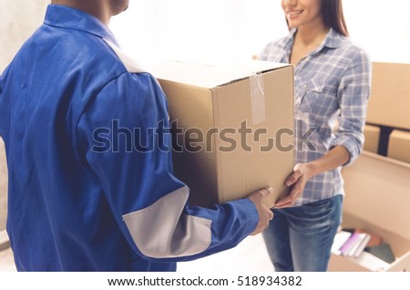 Cropped image of beautiful girl smiling while getting a delivery. Handsome worker is holding a box