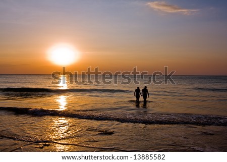 romantic couple holding hands in the ocean at sunset