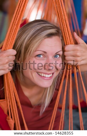 attractive female peeking through ropes of a hammock chair