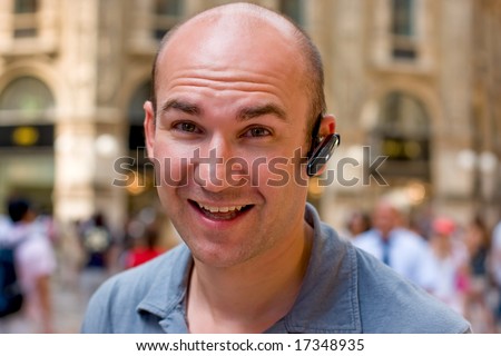 smiling man with headset in busy mall