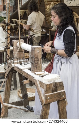 El Alamo, Madrid, Spain . May 1, 2015: A woman disguised as medieval personage works doing sculptures in stone on a medieval market in Spain
