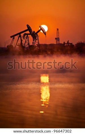 Oil rigs silhouette over orange sky